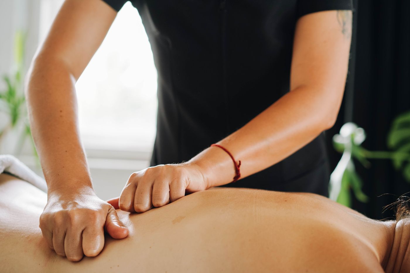 A therapist applies deep-tissue massage pressure to the client's back